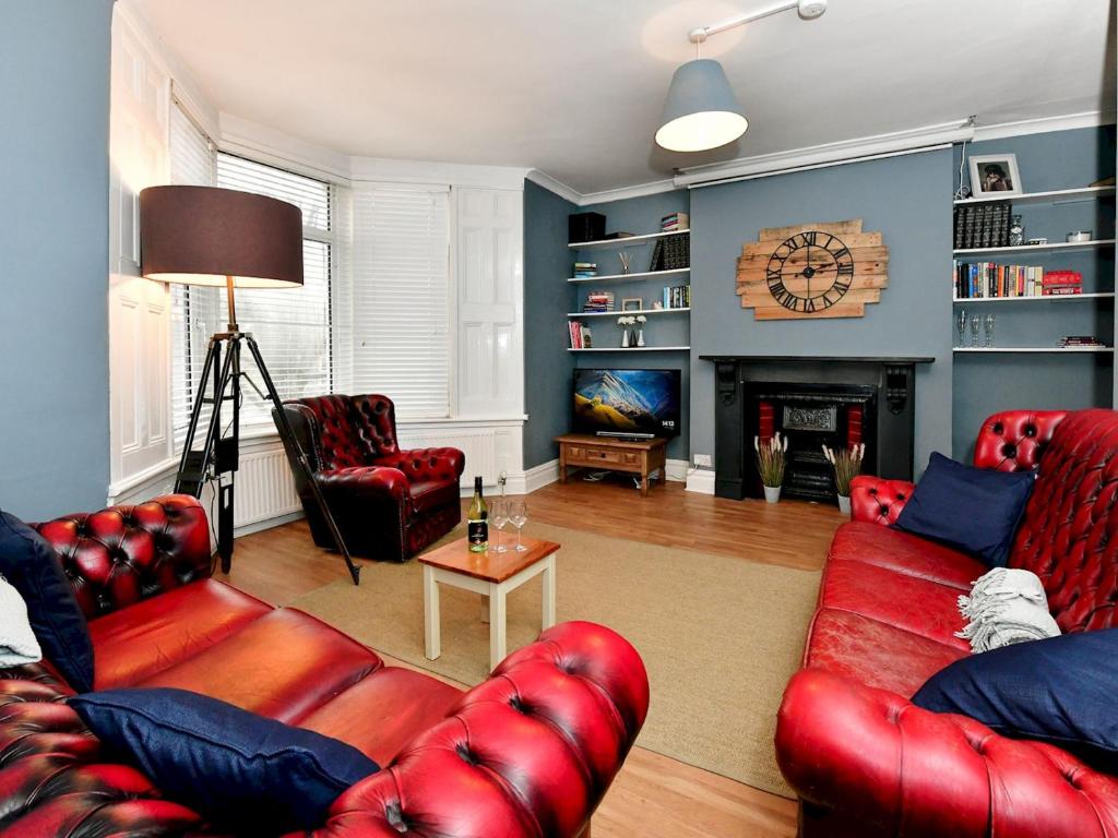 Elle comprend un salon doté d'un mobilier en cuir rouge et d'une cheminée. dans l'établissement Pass the Keys Spacious 3 Bedroom Apartment Close to City Centre, à Cardiff