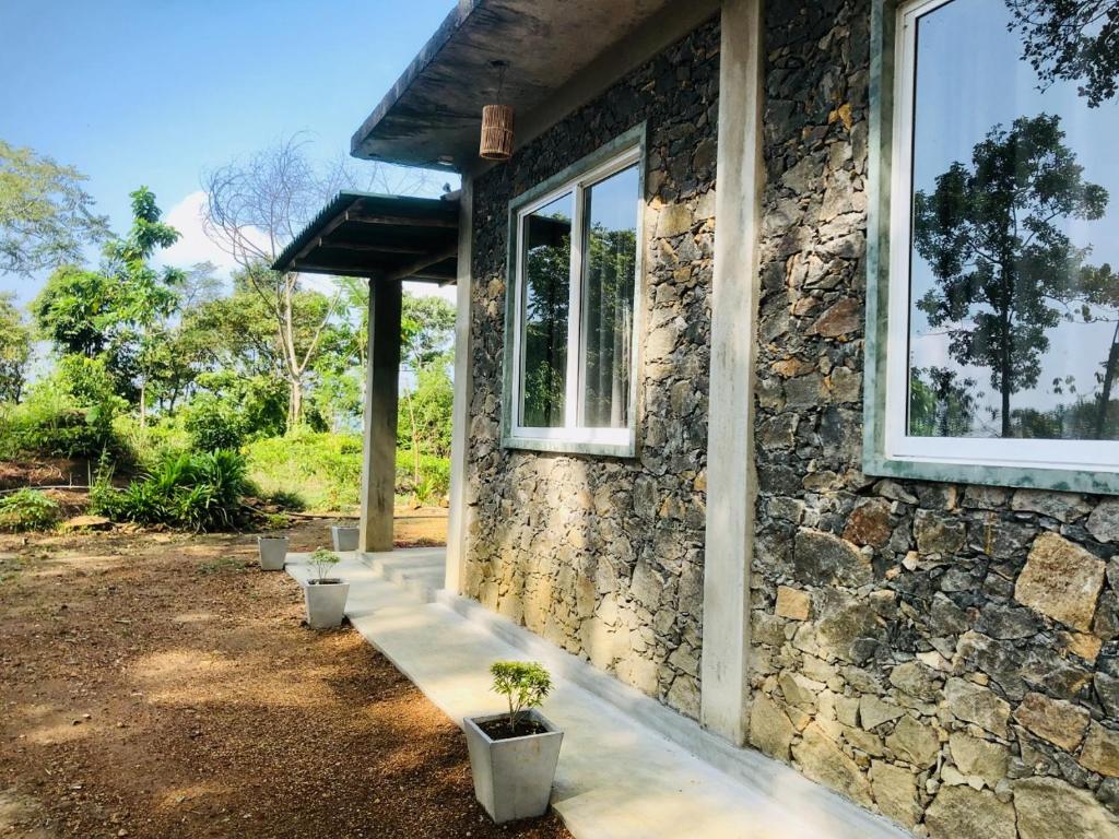 ein Steinhaus mit einem Fenster und Topfpflanzen in der Unterkunft Palabaddala Tea and Eco Lodge in Ratnapura