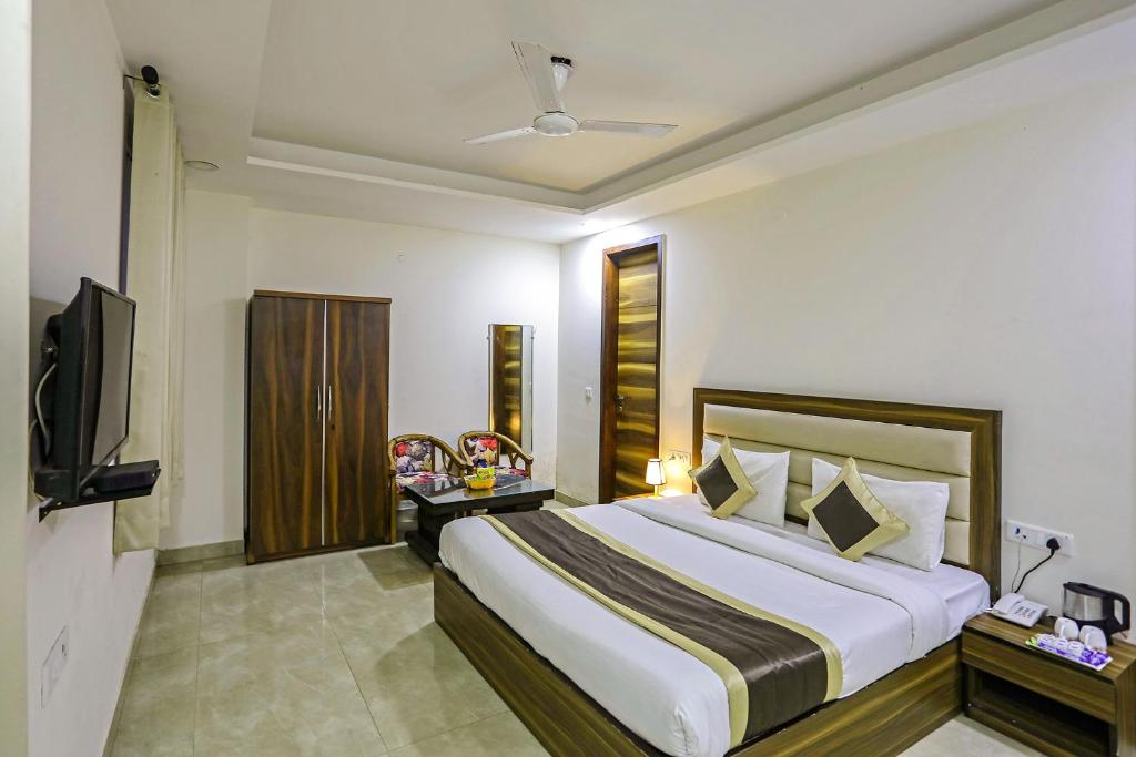 een slaapkamer met een groot bed en een televisie bij FabHotel White House BNB in New Delhi