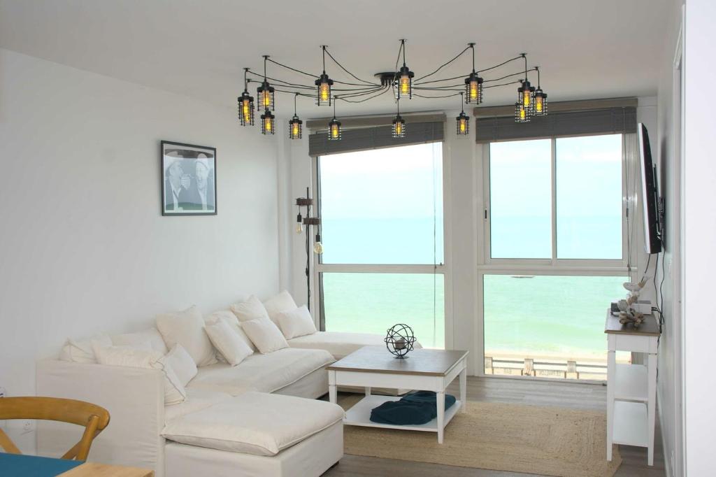 a living room with a white couch and a chandelier at Les pieds dans l eau ! in Fécamp