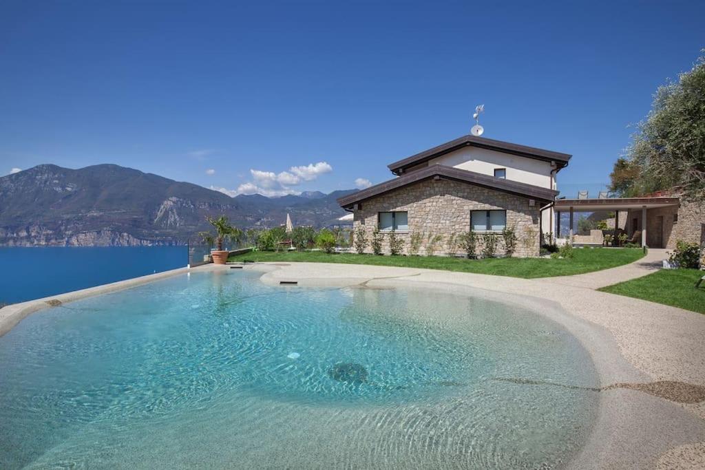 a large swimming pool in front of a house at Villa Divina - APT Divina con piscina e vista lago in Castelletto di Brenzone