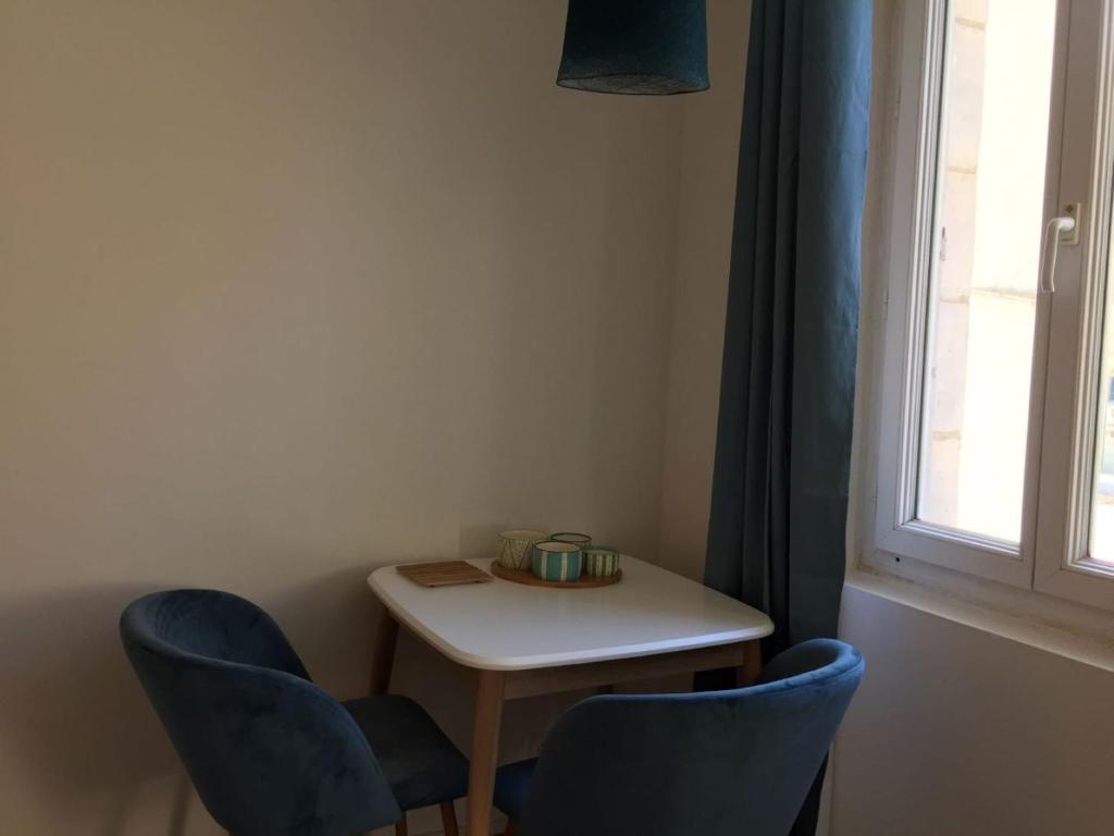 a small table with two blue chairs and a window at L'ELEGANTE in Fécamp