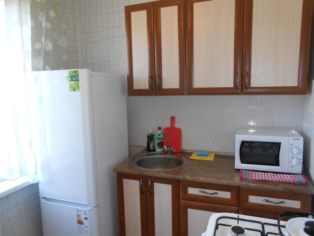 una pequeña cocina con fregadero y nevera blanca en Уютная однокомнатная квартира, en Almaty