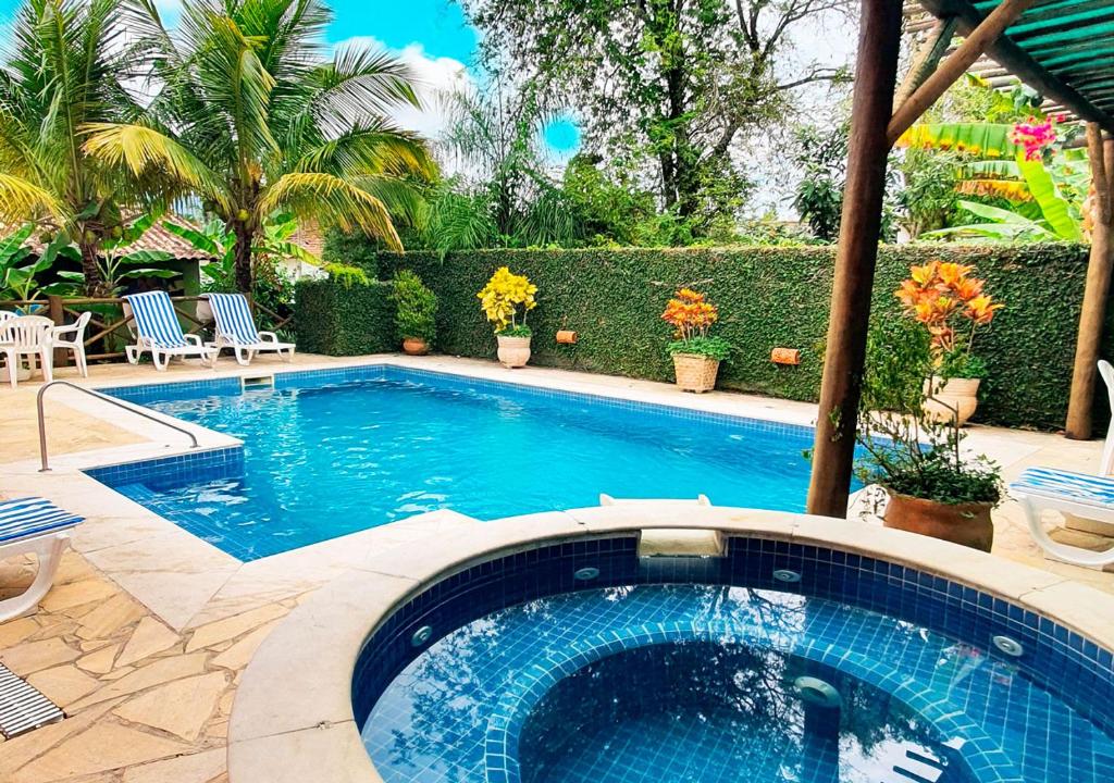 una piscina en un patio con sillas y plantas en VELINN Pousada Villa Caiçara, en Ilhabela