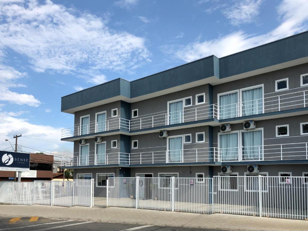 an apartment building with a fence in front of it at Sense Hotel Araucária in Araucária