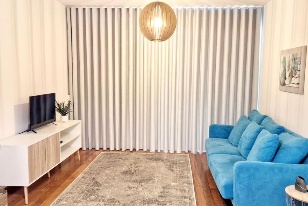 uma sala de estar com um sofá azul e uma televisão em Ocean Pearl Apartment K no Funchal