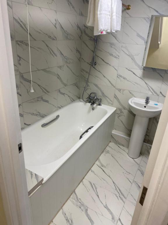 a white bathroom with a tub and a sink at 27 Argyle Square in London