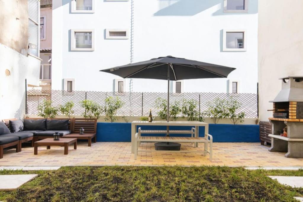 a patio with a bench and an umbrella at Lisbon Intendente Terrace Apartment with BBQ in Lisbon