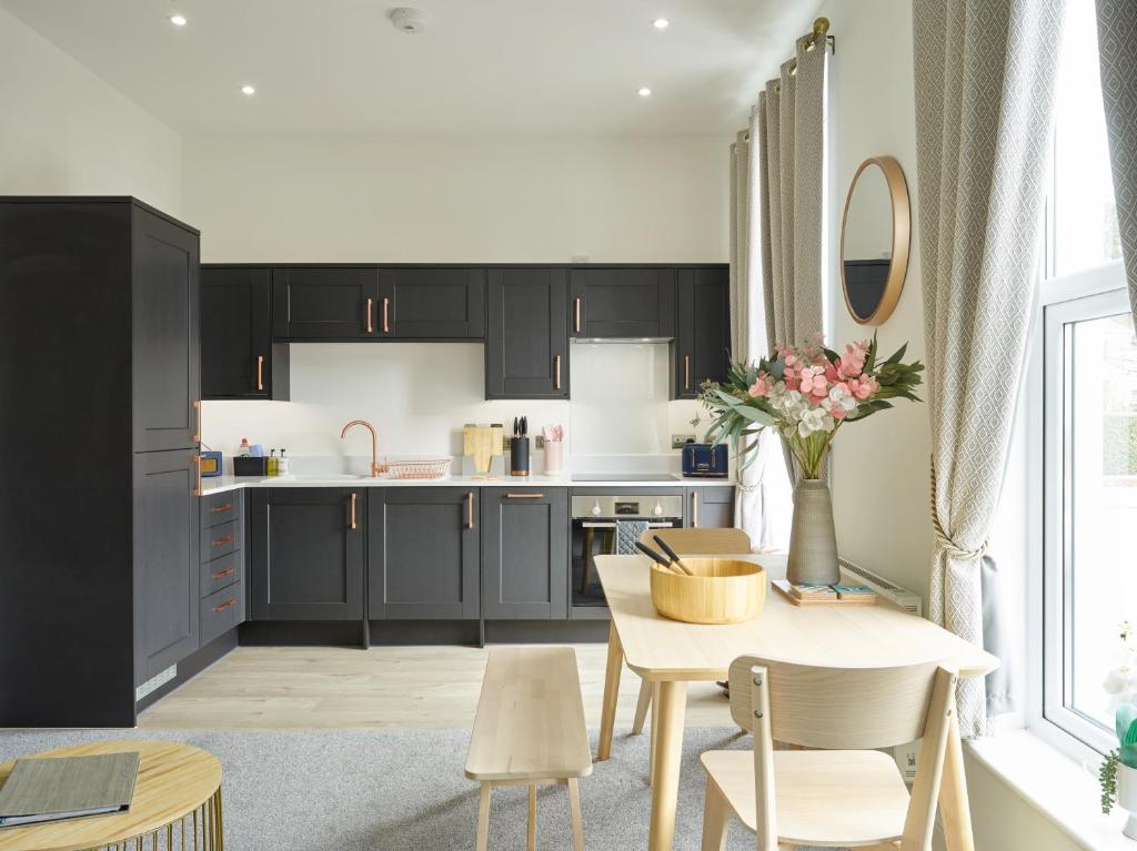 una cucina con armadi neri, tavolo e sedie di Curb Properties - Super 2 Bed Apartment 5 Min From Town Centre a Cheltenham