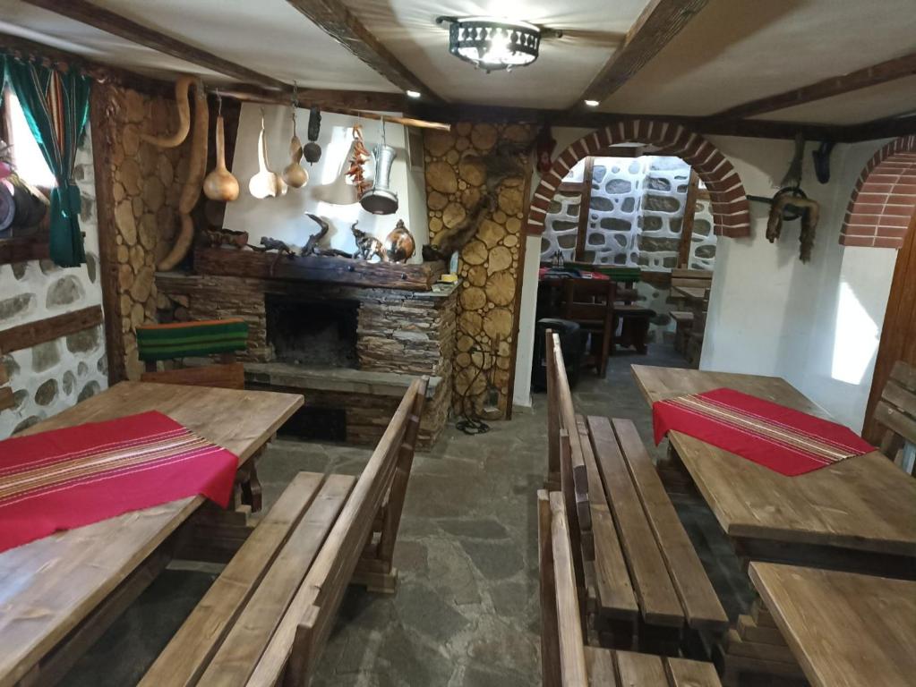 a restaurant with wooden tables and a fireplace at Petar Guest House in Bansko