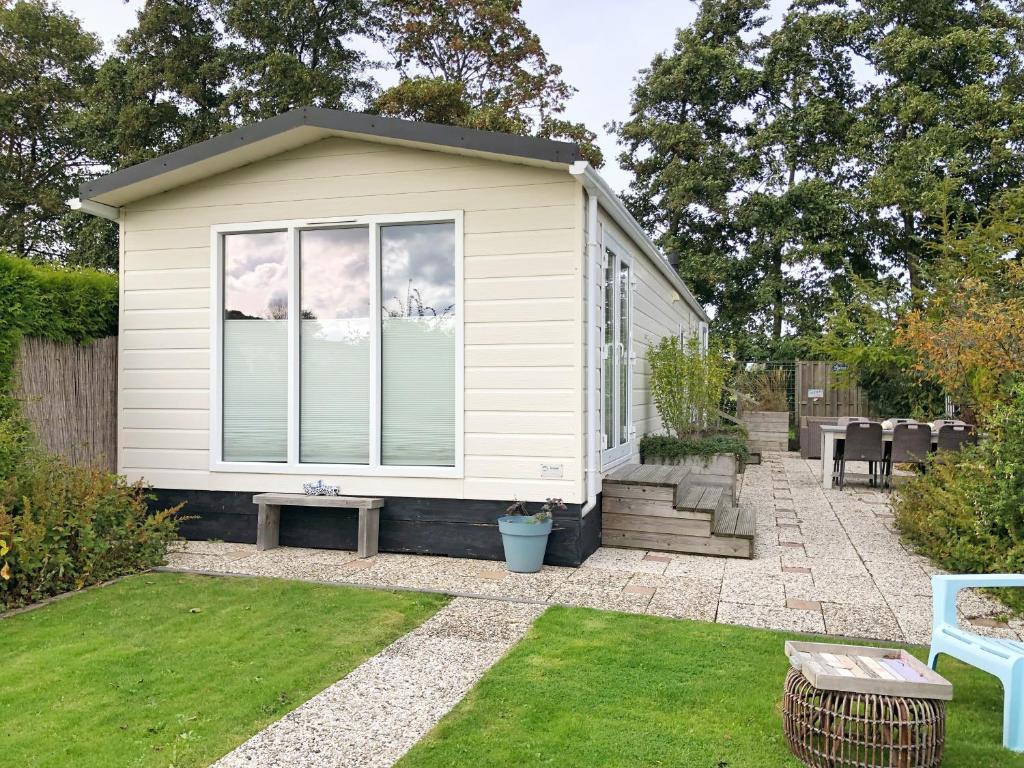 a tiny house in a garden with a patio at Chalet 538 op Recreatiepark De Wielen in Sint Maarten
