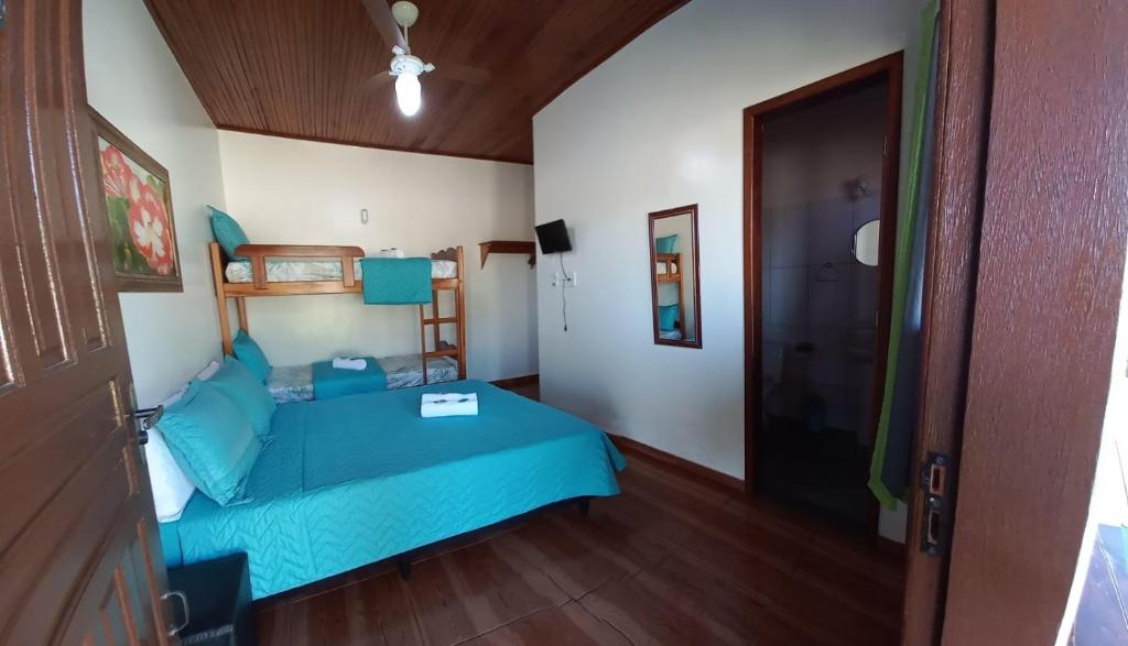 um quarto com uma cama azul e piso em madeira em Pousada Baía do Sol Vilatur em Saquarema