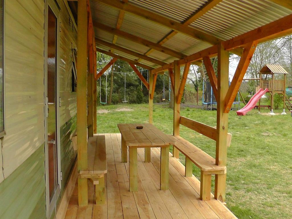 a wooden porch with a picnic table and a playground at NOCLEG WYSPA WOLIN in Warnowo