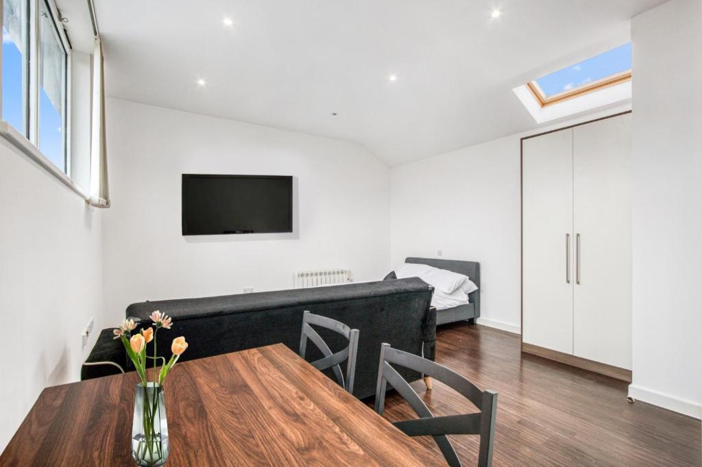 a living room with a table and a bedroom at Stylish Studio by Heathrow Airport in London