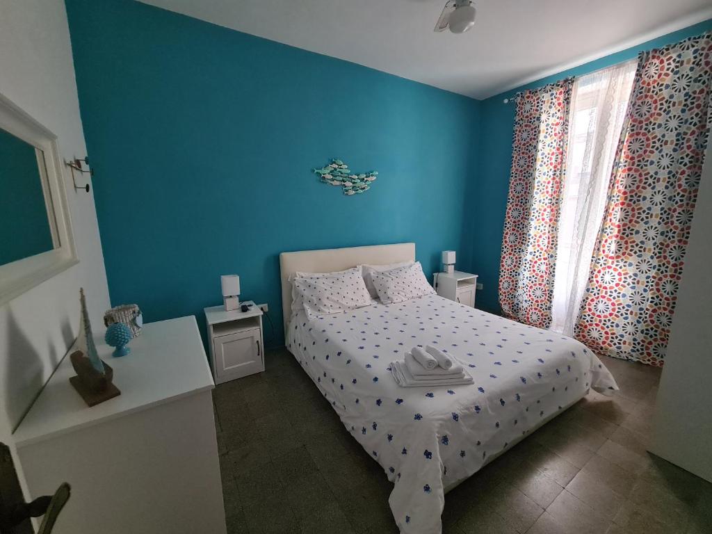 a blue bedroom with a bed and a window at Le Petit Bouganville in Salerno