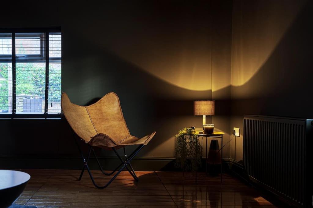 einen Stuhl in einem Zimmer mit einer Lampe und einem Fenster in der Unterkunft BOHOME moody 2 bed garden cottage Macclesfield centre in Macclesfield