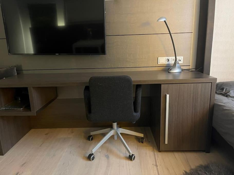 a desk with a chair and a television and a lamp at Gemütliches Apartment Nähe Medienhafen S-Bahn und free Parken in Düsseldorf