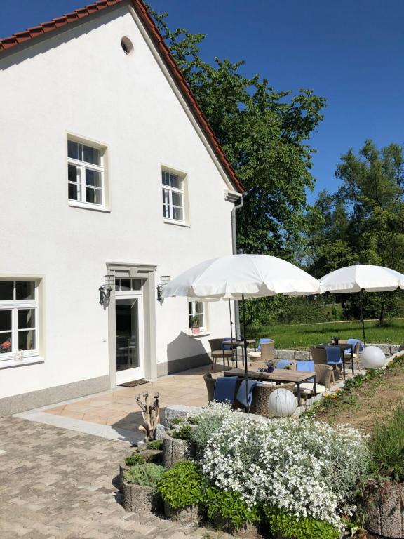 een wit huis met parasols en een patio bij Alte Leimsiederei in Herrnhut