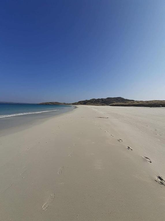 a group of footprints in the sand on a beach at Logan Home in Stornoway