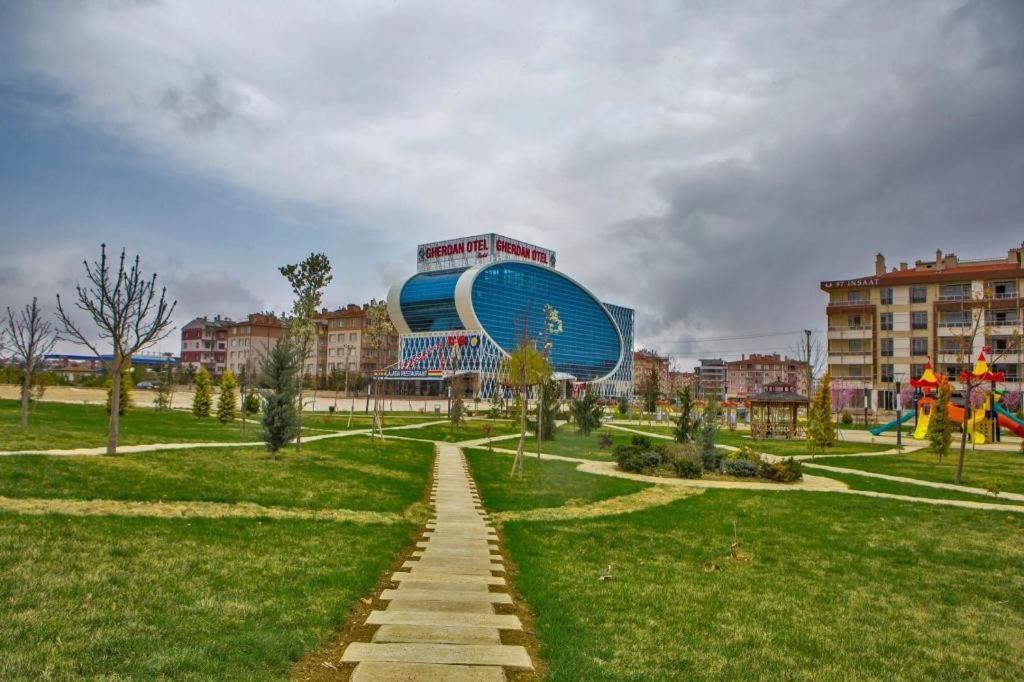 un parc avec un grand bâtiment en arrière-plan dans l'établissement GHERDAN GOLD OTEL, à Konya
