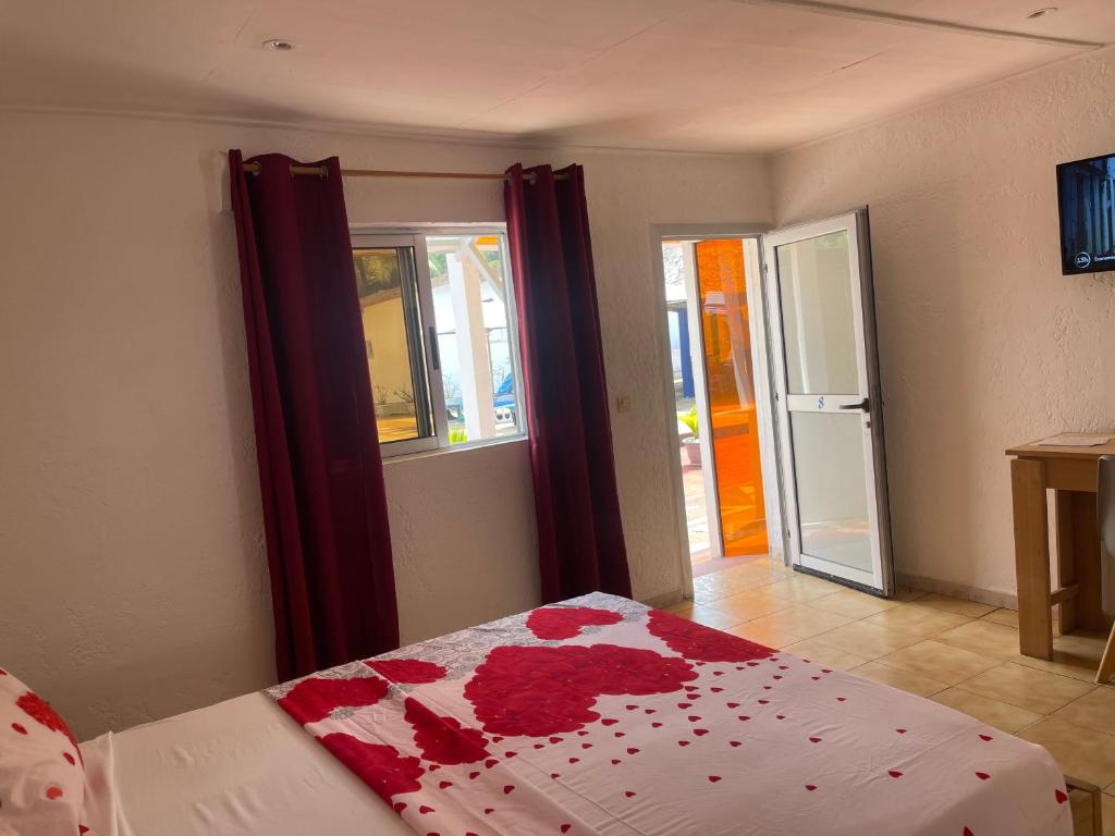 Un dormitorio con una cama con flores rojas. en Hotel La Madrague en Grand-Bassam