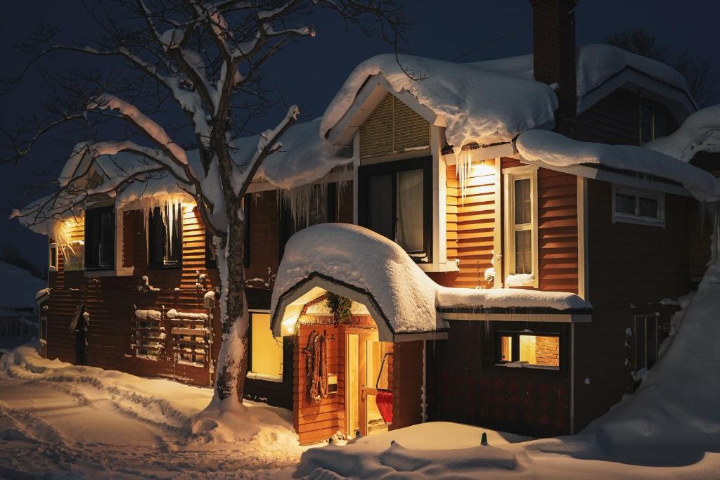 una casa cubierta de nieve por la noche en Country Inn Milky House, en Niseko
