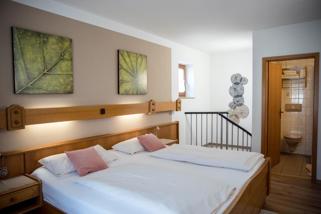 a bedroom with a bed with white sheets and pink pillows at Geisbergerhof in Bad Birnbach