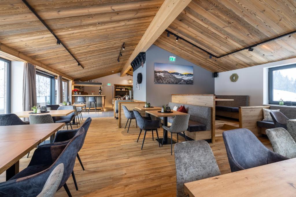 un restaurante con techos de madera, mesas y sillas en Aparthotel Fuxbau en Flachau