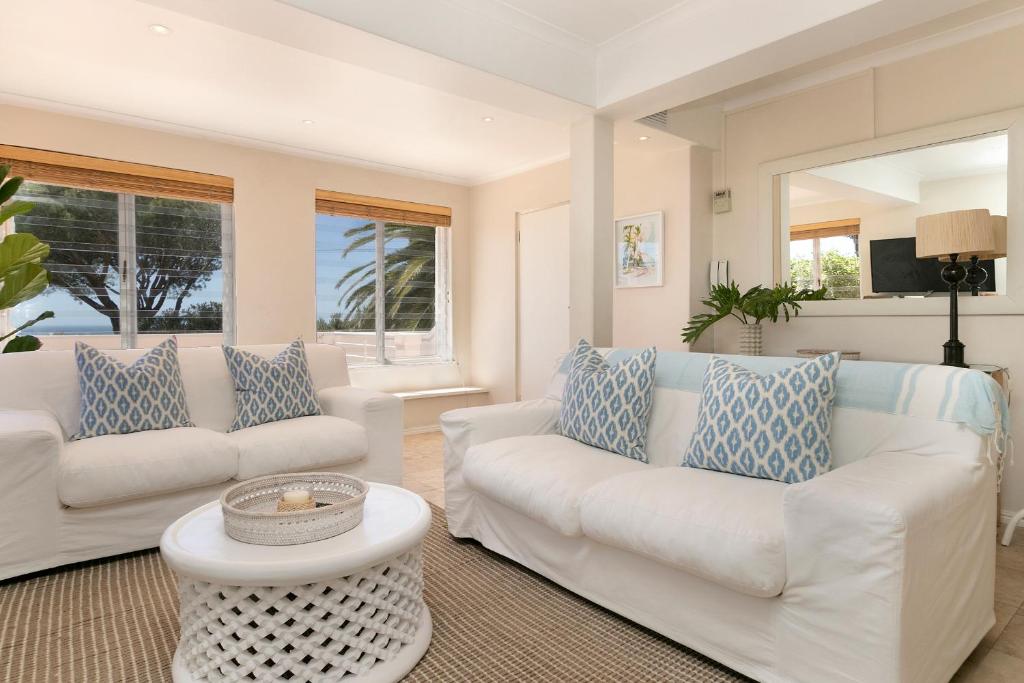 una sala de estar con 2 sofás blancos y una mesa. en Ingleside Luxury apartment by Totalstay en Ciudad del Cabo