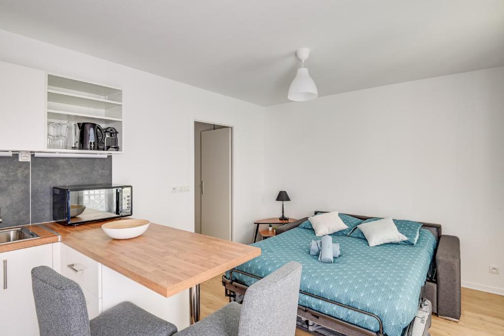 a living room with a bed and a wooden table at La Vallée-Chatenay Malabry in Châtenay-Malabry