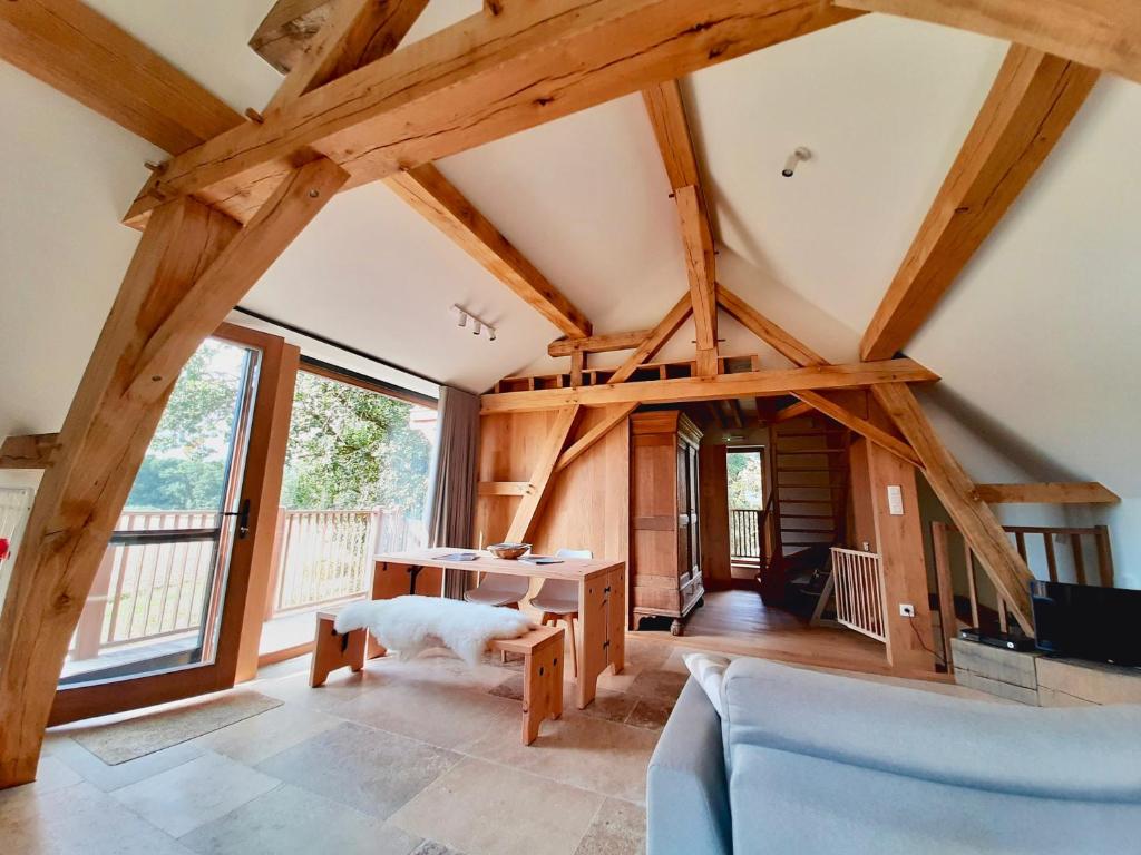 a living room with wooden ceilings and large windows at Lodge op de Berg in Bree