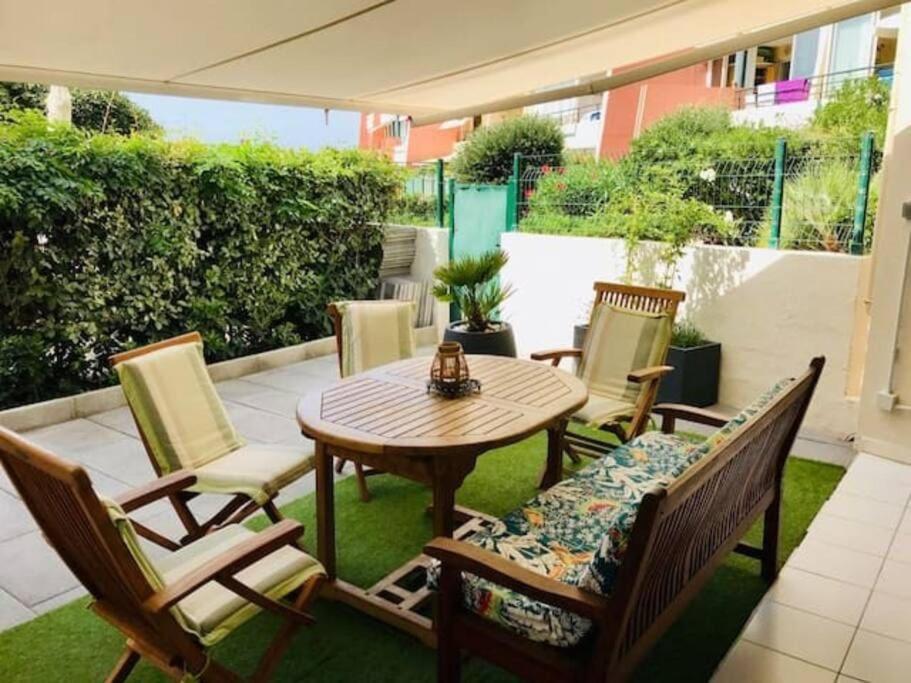 a patio with a table and chairs on the grass at ''Croisette'' Appartement rez de jardin accès direct plage ! in Sète