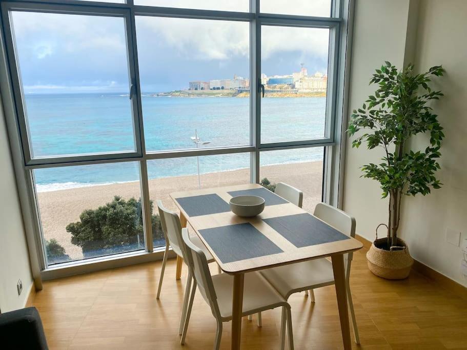 una sala da pranzo con tavolo e vista sulla spiaggia di Apartamento acogedor con vistas al mar. a La Coruña