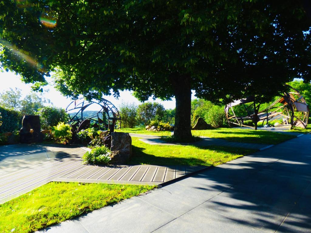 a park with a tree and a sidewalk at Auberge Les Grillons in Meyras