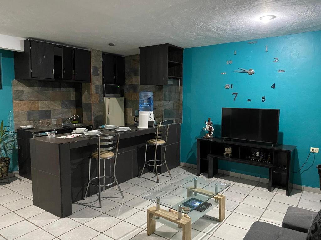 a kitchen with a blue wall with a counter and stools at Bonito Departamento Verde con terraza in Cholula