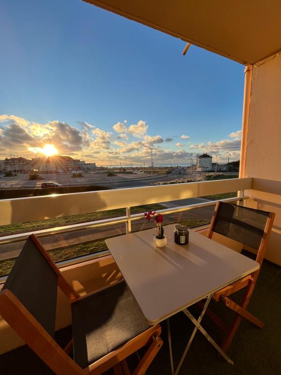 a table and chairs on a balcony with a view at Appartement cosy avec vue mer in Stella-Plage