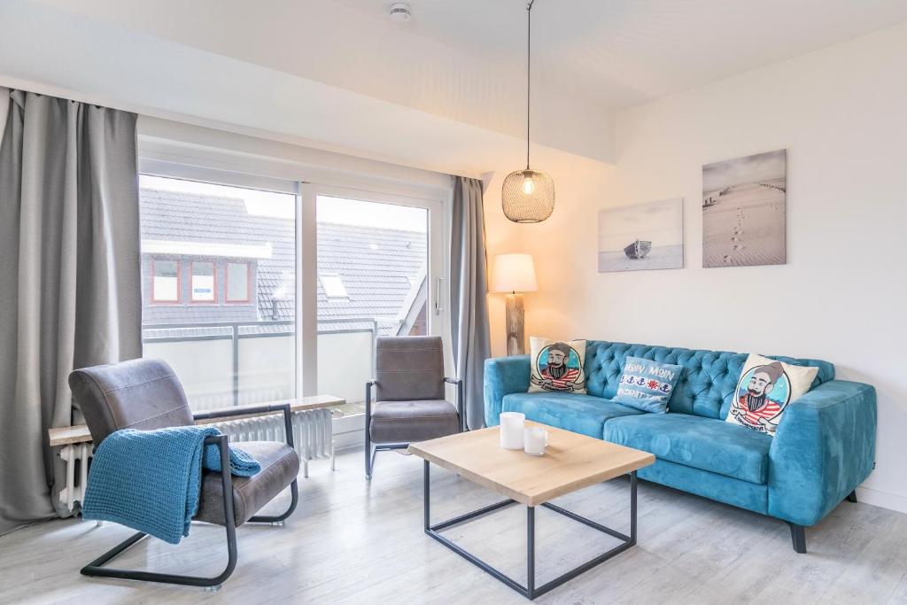 a living room with a blue couch and chairs at "Haus Deichlodge" deichlodge lodge fünf in Büsum