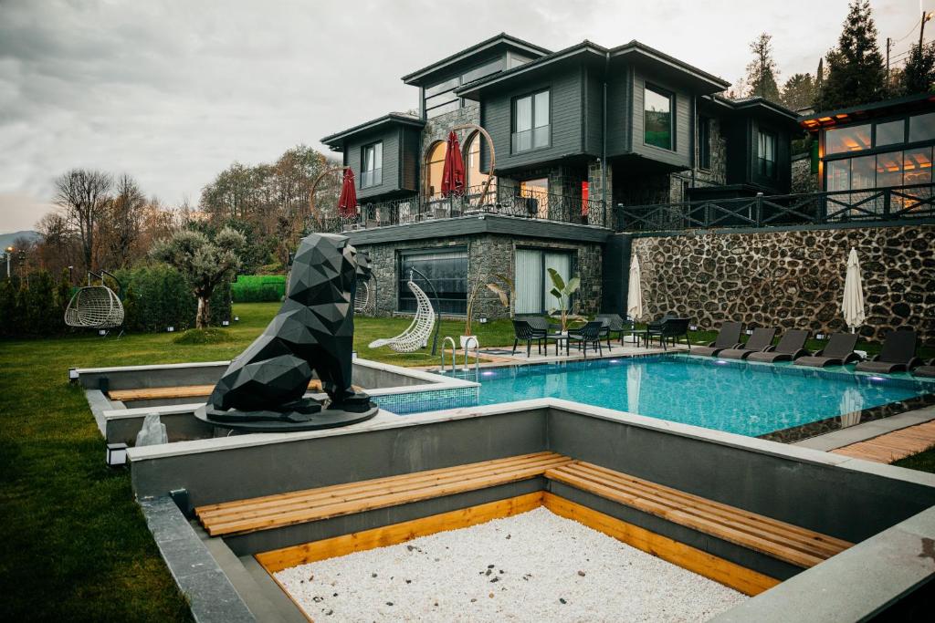 ein Haus mit einem Pool und einer Statue davor in der Unterkunft Çathan Art Hotel in Ayder Yaylasi