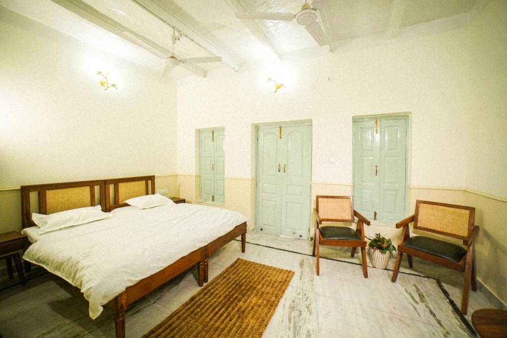 a bedroom with a large bed and two chairs at Shree Krishna Bhakti Ashram in Vrindāvan