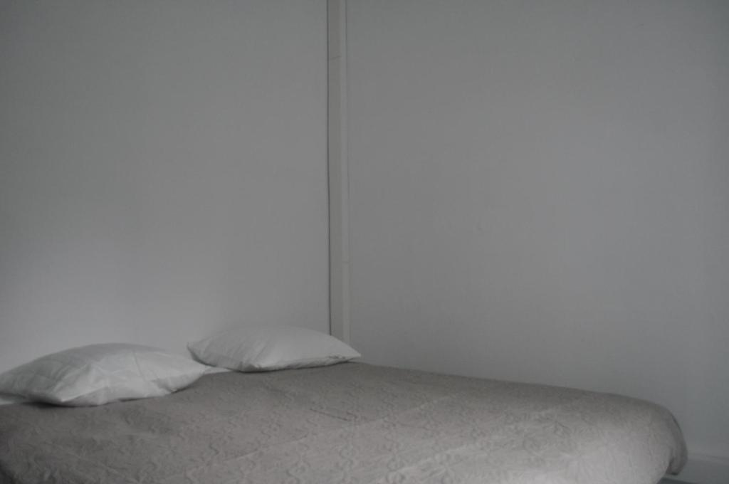 a white bedroom with a bed with white sheets and pillows at Charmant T3 au cœur de Agen Sud in Agen