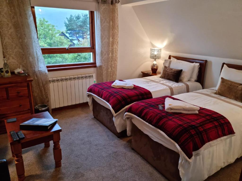 a hotel room with two beds and a window at Lochview Guest House in Ullapool