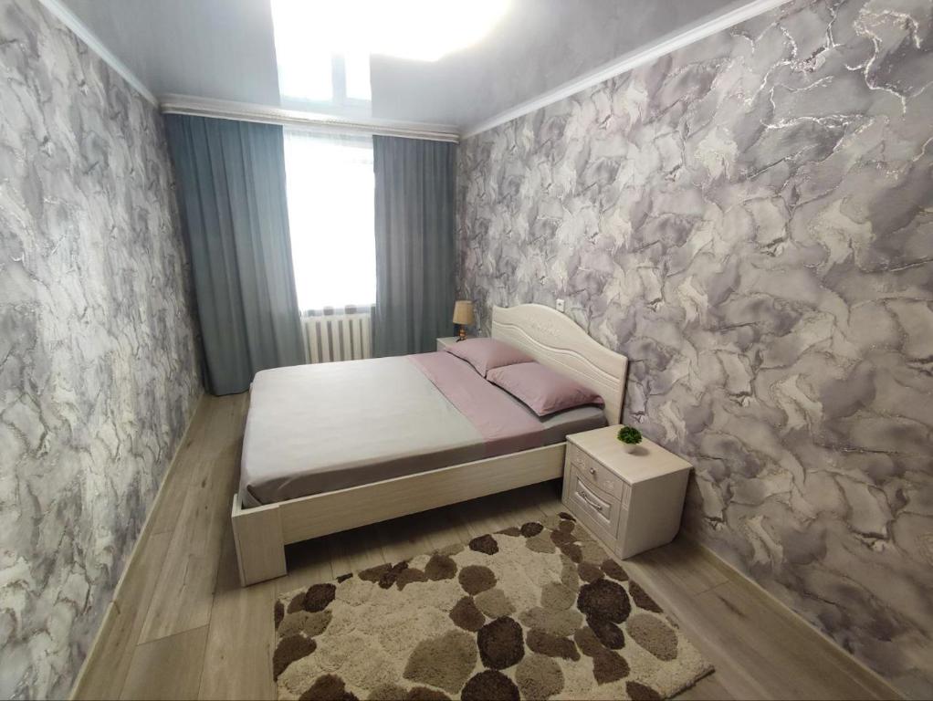 1 dormitorio con cama y pared de piedra en 2-х комнатная квартира в центре на ул.Бородина 107 en Kostanái