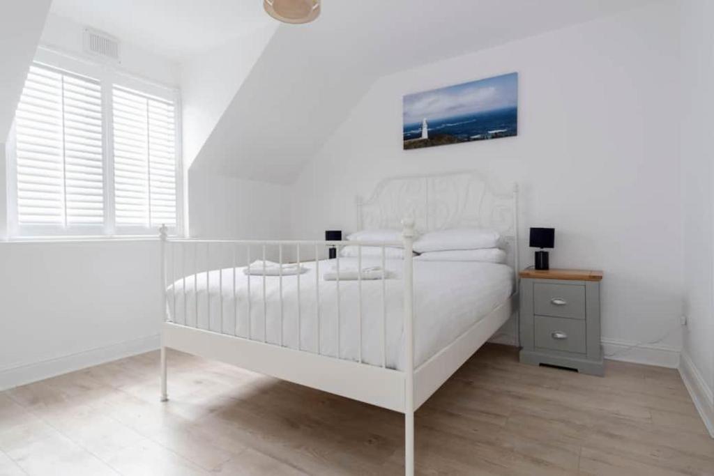 a white bedroom with a white bed and a window at Modern newly refurbished house 10 minute walk from Lahinch in Lahinch