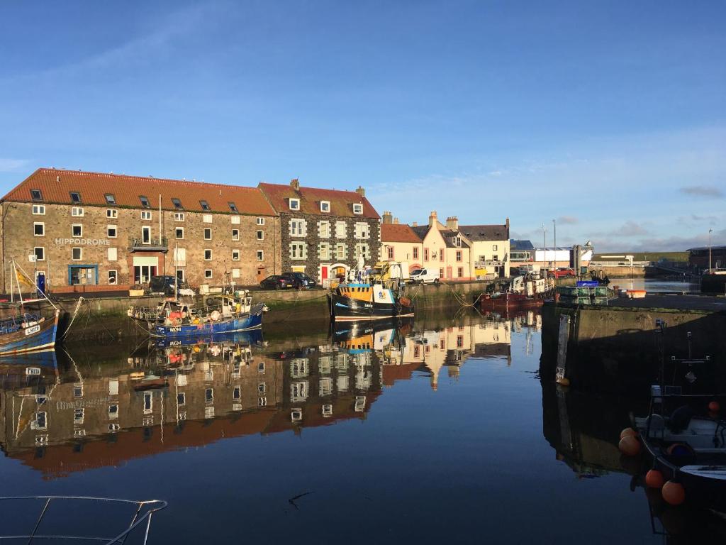 a body of water with boats in a city at Harbourside Apartment in Eyemouth