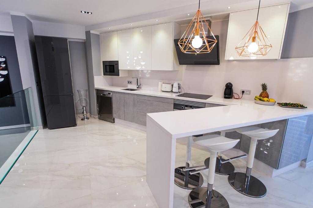 une cuisine avec un grand comptoir blanc et des tabourets dans l'établissement Luxury 2 bedroom apartment in Los Cristianos, à Los Cristianos