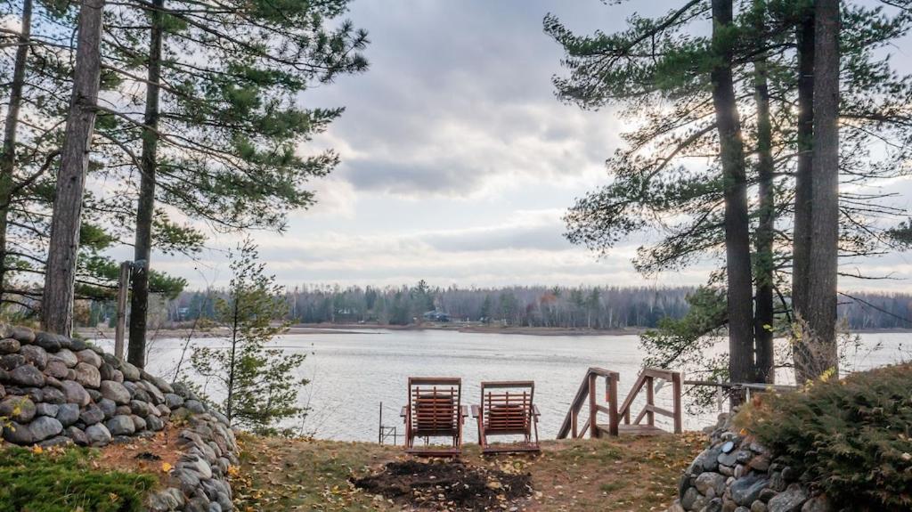 zwei Stühle am Ufer eines Sees in der Unterkunft TheLake House in Tomahawk