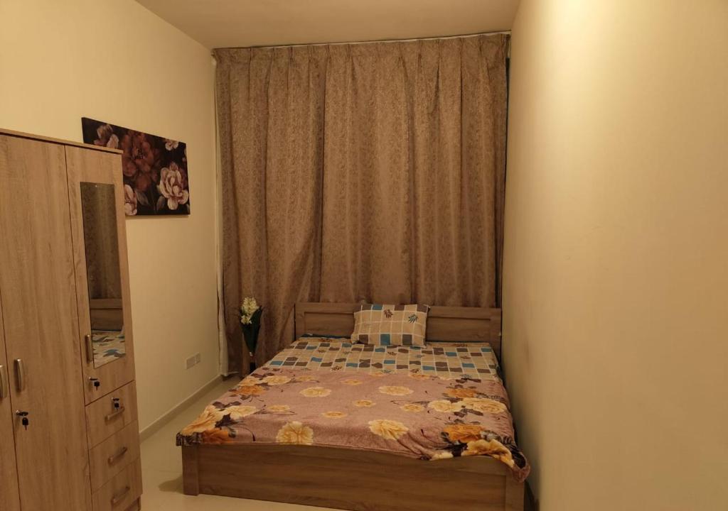 ein Schlafzimmer mit einem Bett und einem Fenster mit einem Vorhang in der Unterkunft Private Room In shared apartment in heart of Ajman in Ajman 