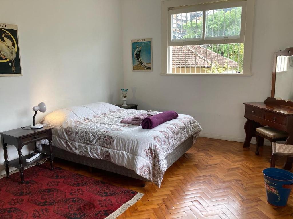 a bedroom with a bed and a desk and a window at Casa Verde em Petrópolis in Petrópolis