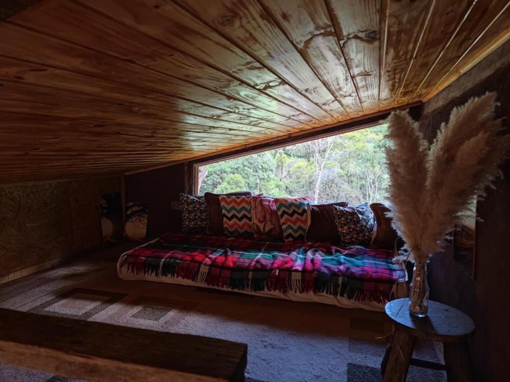 Un sofá sentado en una habitación con ventana. en Middle House, en Campos do Jordão