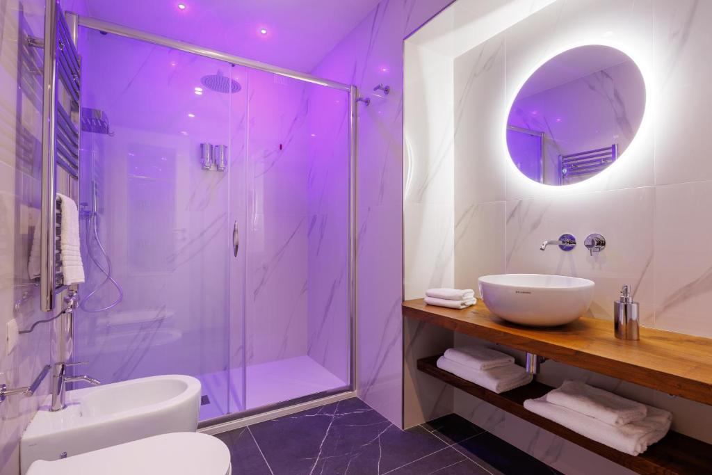 La salle de bains est pourvue d'un lavabo et d'une douche avec un éclairage violet. dans l'établissement SM Mellini Relais B&B, à Rome